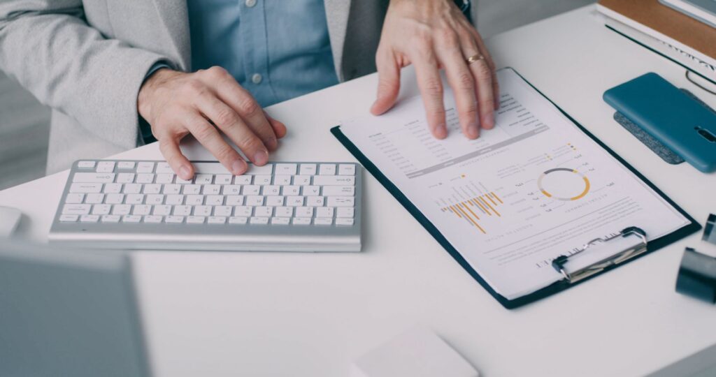 a man working with a financial report and keyboard in an office setting.