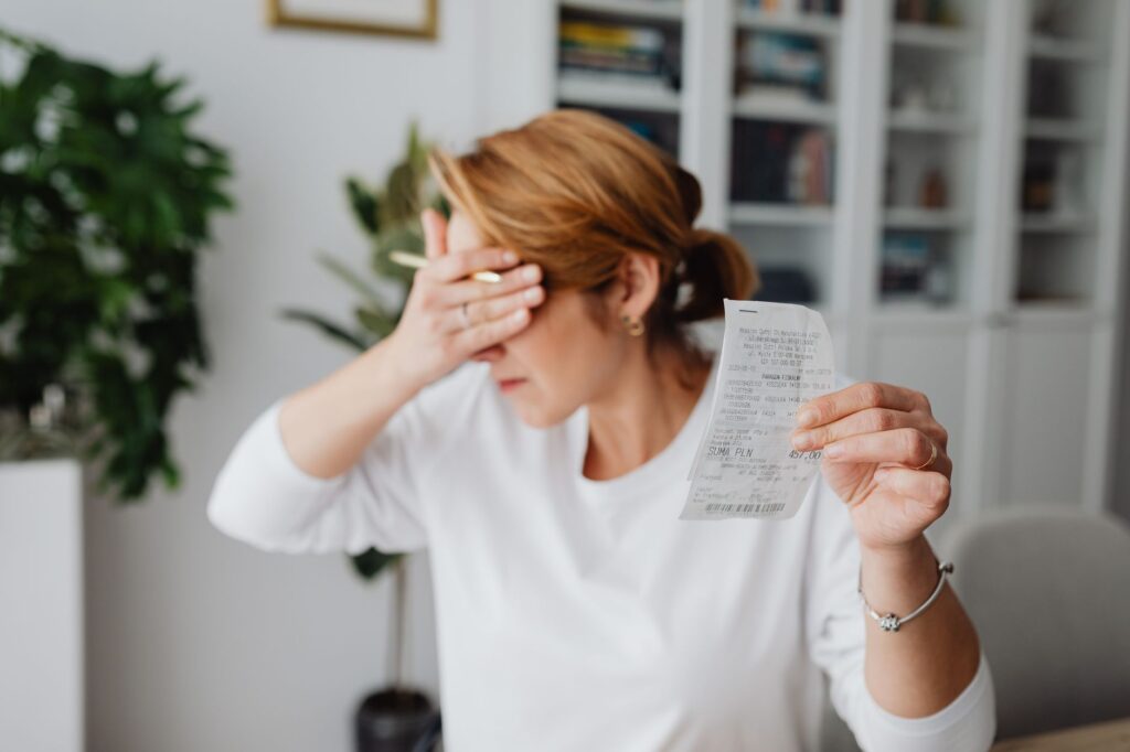 woman experiencing stress while reviewing household expenses at home.