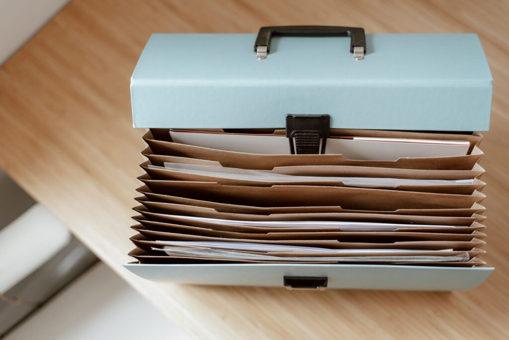 from above of briefcase for documents with papers placed on wooden table in daytime