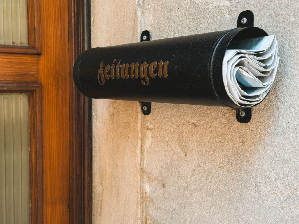 stylish black newspaper holder on a wall in bad berneck, germany, holding newspapers.