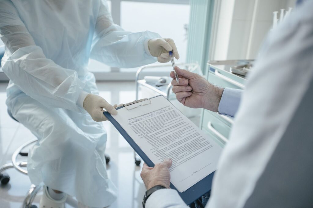 a doctor hands a clipboard to a patient for signature, highlighting medical professionalism.